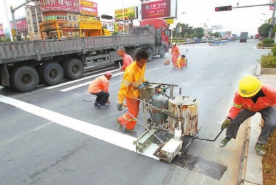 工人在用手推熱熔劃線機施劃標線
