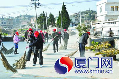 一群特殊的志愿者在軍營村的馬路上開展衛(wèi)生清潔工作。