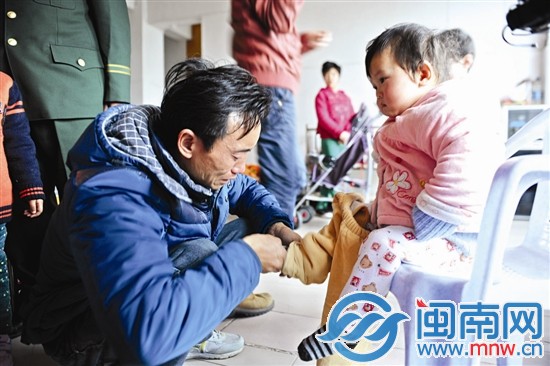 父親給剛睡醒的小女兒穿戴衣服