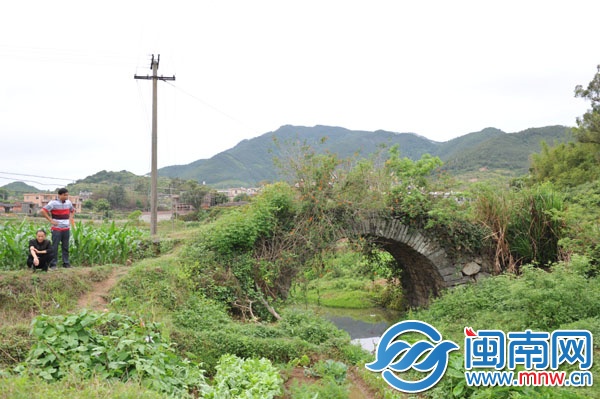 已廢棄的石拱橋，被野草覆蓋，下有溪流，村民稱此路