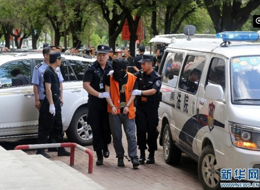 兩名犯罪嫌疑人頭戴面罩，被法警押進(jìn)法庭。