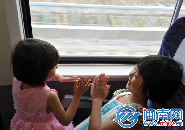 動(dòng)車上，朱心琴姐妹玩拍手游戲打發(fā)時(shí)間